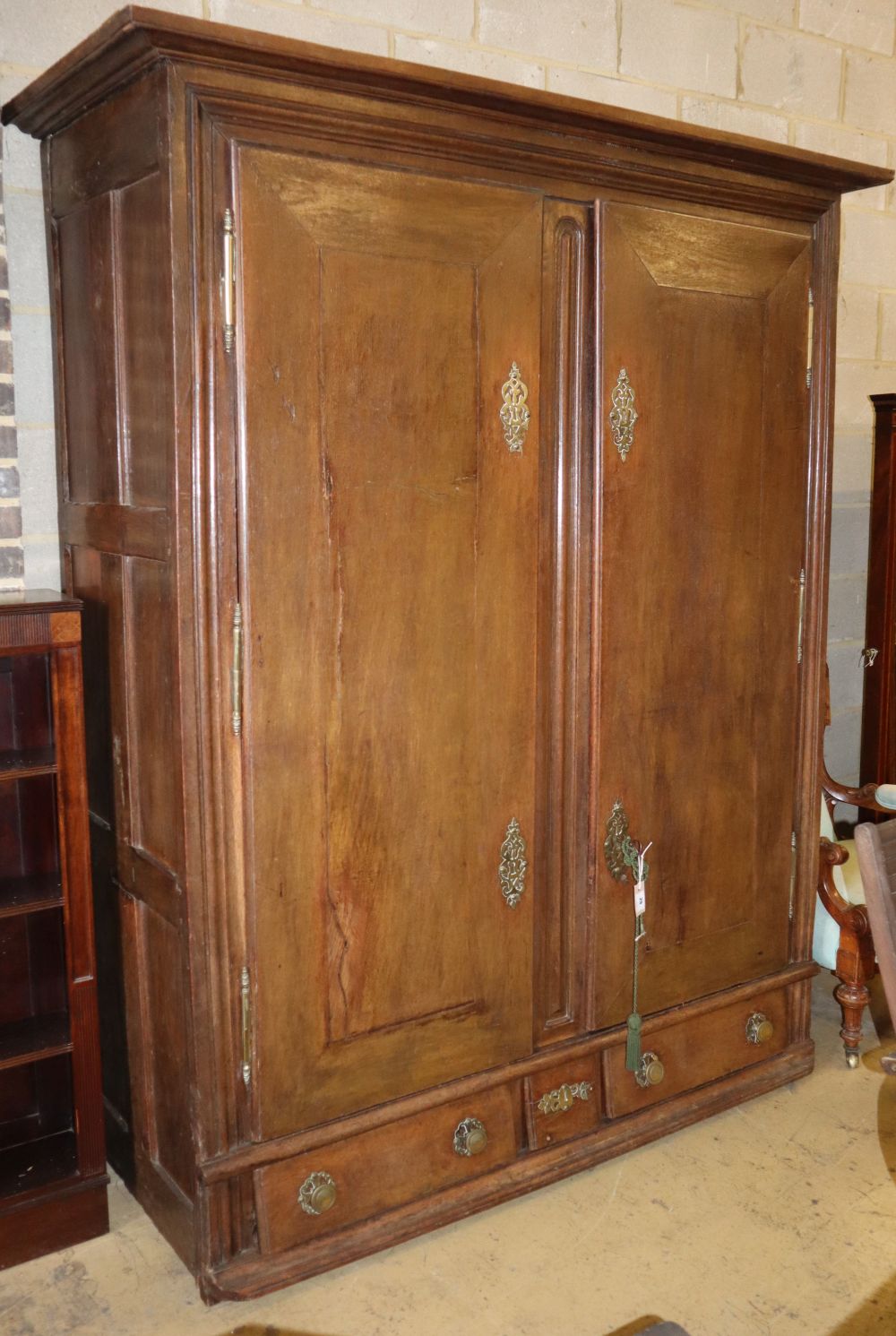 An 18th century Normandy oak two door armoire with brass escutcheons and buttressed hinges, W.178cm, H.218cm
